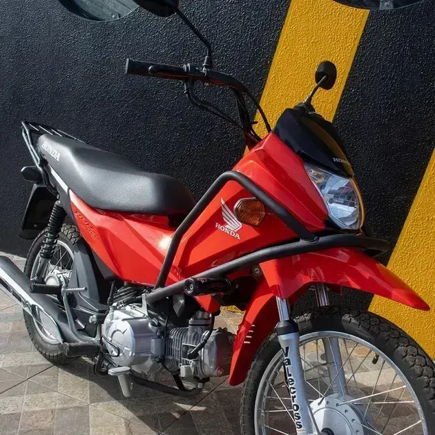 Motocicleta lateral em frente a uma parede texturizada preta com faixas amarelas.